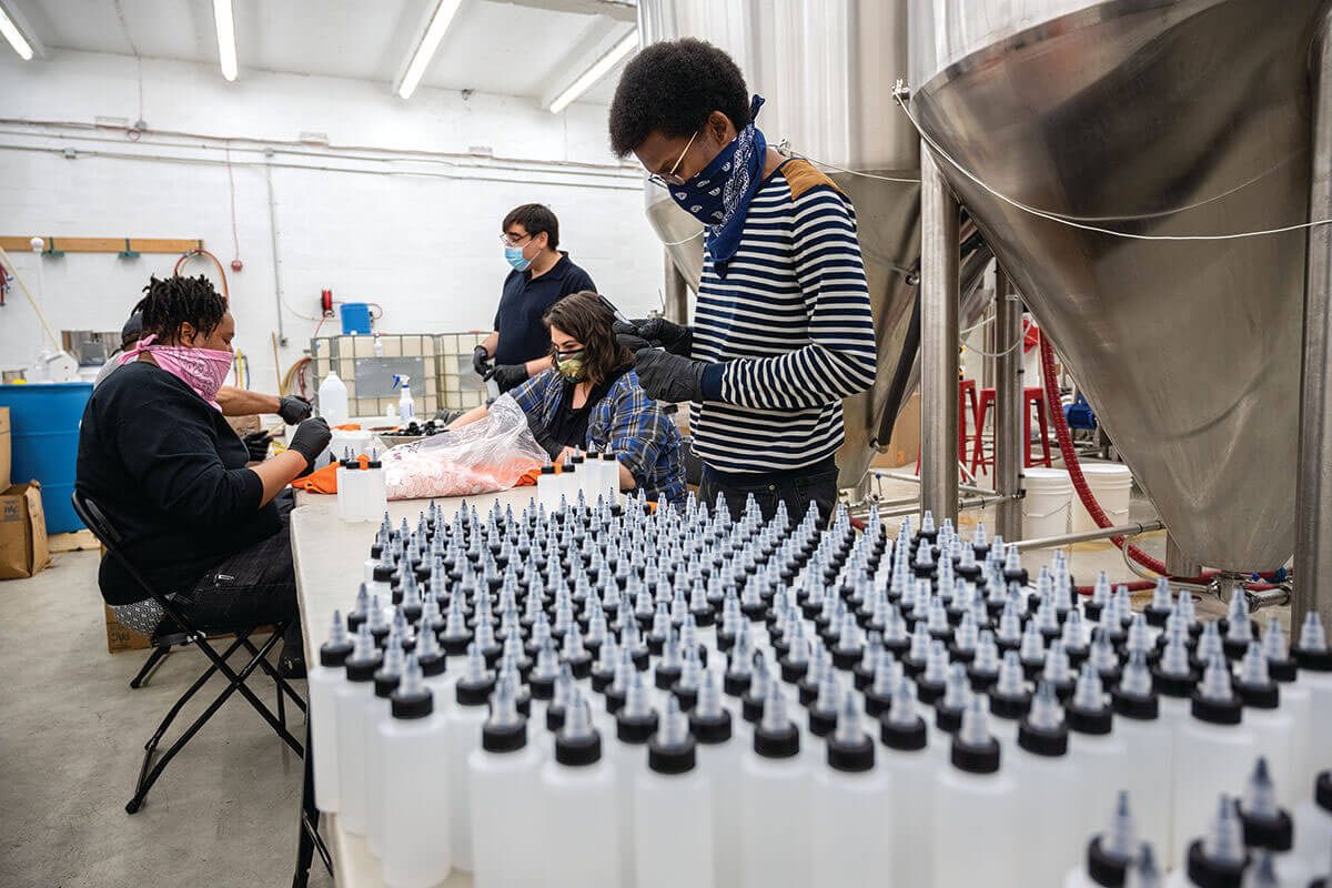A picture volunteers making and packaging cleaning solutions like hand sanitizer.